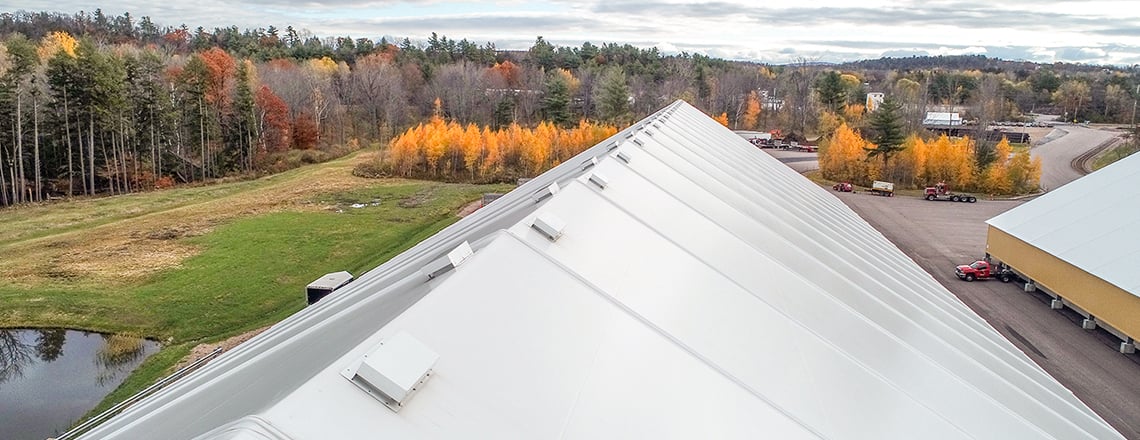 tension fabric building roof showing roof ventilation with autumn trees in background